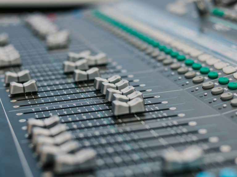 Mischpult mit mehreren Schiebereglern und Tasten.